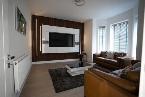 a living room with a couch and a tv at Luxury 6 Bed near city centre with Cinema Room & games room plus 5 bathrooms in Manchester