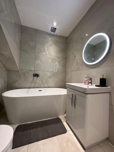a bathroom with a tub and a sink and a mirror at Luxury 6 Bed near city centre with Cinema Room & games room plus 5 bathrooms in Manchester