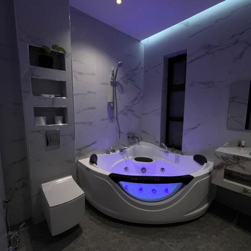 baño con bañera grande con iluminación púrpura en شاليهات سيليا الفندقية, en Al Mubarraz