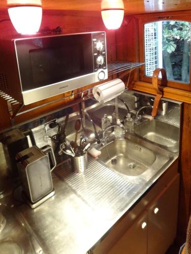 une cuisine avec un évier et un micro-ondes dans l'établissement Bateau, Péniche Marboré - Disney, à Lagny-sur-Marne