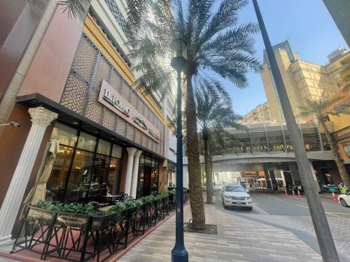 a palm tree in front of a building with tables at Modern Comfort - AlGhurair Mall in Dubai