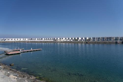 a large body of water with a dock and a bridge at Nasma Luxury Stays - Luxurious Villa with Private Pool & Close to Beach in Fujairah