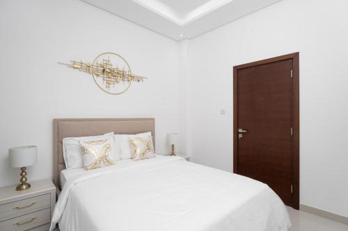 a white bedroom with a bed and a brown door at Nasma Luxury Stays - Luxurious Villa with Private Pool & Close to Beach in Fujairah