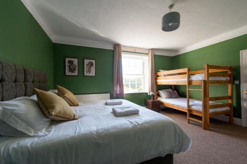 a bedroom with green walls and a bed and bunk beds at FIRS Sleeps 15 Stunning country house with hot tub in Sudbourne