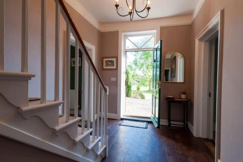 a hallway with a staircase and a glass door at FIRS Sleeps 15 Stunning country house with hot tub in Sudbourne