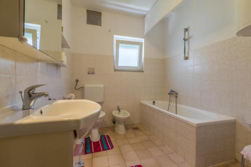 een badkamer met een wastafel, een bad en een toilet bij Viki D in Dramalj