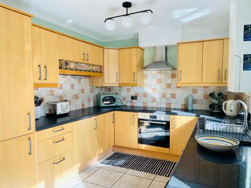 cocina con armarios de madera y encimera negra en Tanglewood Close, 3 Bedroom house, Abergavenny with private parking,, en Abergavenny