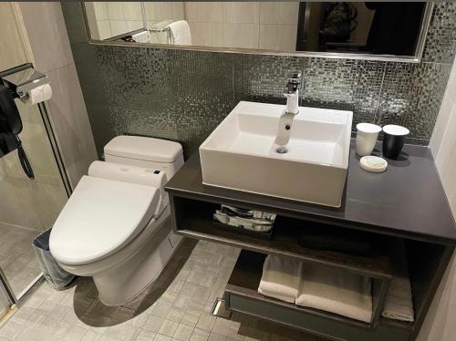 a bathroom with a white toilet and a sink at At Home Hotel Ximen in Taipei