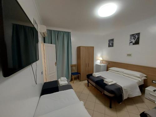 a bedroom with two beds and a flat screen tv at Hotel Positano in Rome