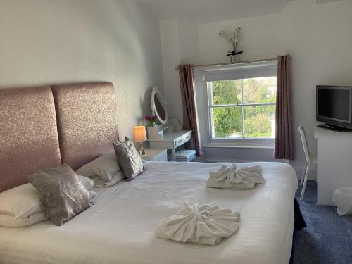 a bedroom with a bed with two pillows and a window at Allerdale in Torquay