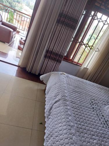 a white bed in a room with a large window at CONVENTION VILLA APART HOTEL in Kigali