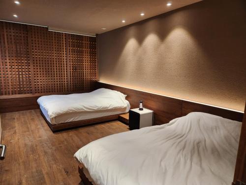 a bedroom with two beds and a wall with at Myeongwolga Poolvilla in Busan
