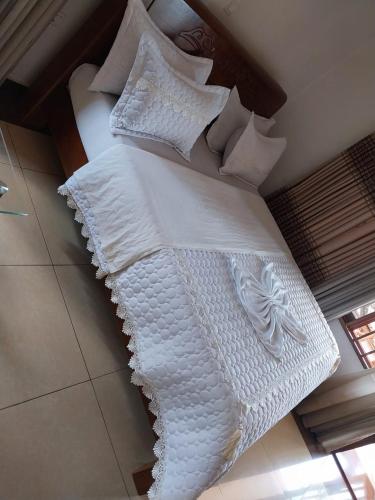 1 cama blanca grande con sábanas y almohadas blancas en CONVENTION VILLA APART HOTEL, en Kigali