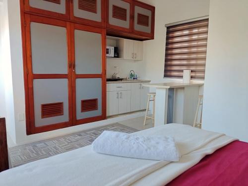 a bedroom with a bed with a red door and a kitchen at Studio Norte, Casa Brisamar in Puerto Morelos