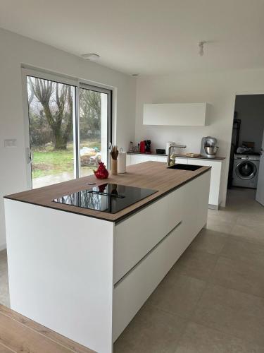 - une cuisine avec un îlot blanc et un comptoir dans l'établissement La Perle du petit Rupembert, à Wimille