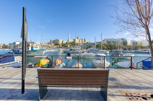 a wooden bench sitting next to a marina with boats at Spacious 2BR home with Large, Private Sun Terrace by 360 Estates in Taʼ Xbiex