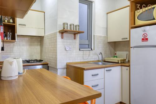 a kitchen with white cabinets and a wooden table at Spacious 2BR home with Large, Private Sun Terrace by 360 Estates in Taʼ Xbiex
