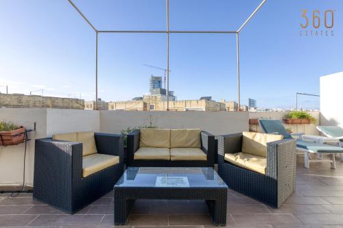 a patio with two chairs and a coffee table at Spacious 2BR home with Large, Private Sun Terrace by 360 Estates in Taʼ Xbiex