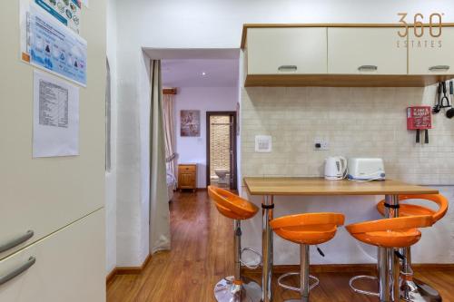 a kitchen with a table and two orange stools at Spacious 2BR home with Large, Private Sun Terrace by 360 Estates in Taʼ Xbiex