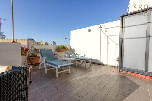 a patio with two chairs and a table on a roof at Spacious 2BR home with Large, Private Sun Terrace by 360 Estates in Taʼ Xbiex