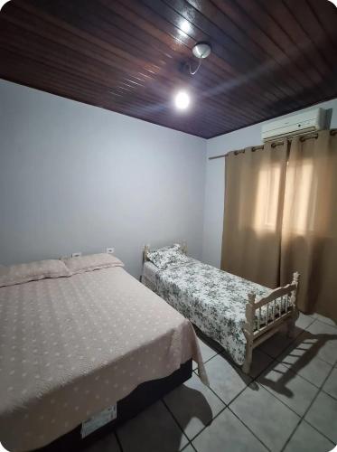 een slaapkamer met 2 bedden en een houten plafond bij Casa aconchegante em frente a praia in Ubatuba