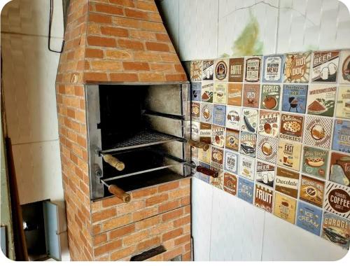 een bakstenen oven met veel stickers op de muur bij Casa aconchegante em frente a praia in Ubatuba