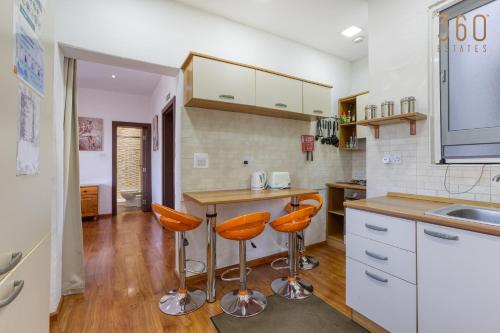 a kitchen with orange bar stools and a counter at Spacious 2BR home with Large, Private Sun Terrace by 360 Estates in Taʼ Xbiex