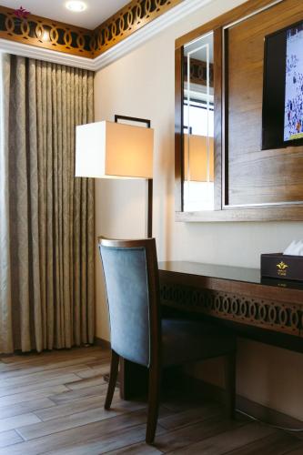 a desk with a lamp and a chair in a hotel room at Violet Al Azizia Hotel MASJID Al Qatari in Makkah