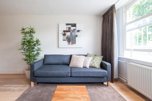 a blue couch in a living room with a window at Museumpark Apartments in Rotterdam