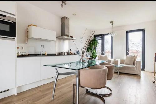 een keuken en een woonkamer met een glazen tafel en stoelen bij 4-bedroom large spacious apartment in Amsterdam