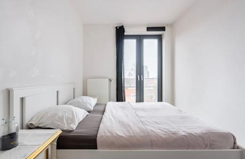 a white bedroom with a large bed and a window at 4-bedroom large spacious apartment in Amsterdam