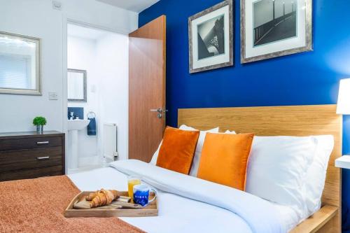 Una cama con almohadas naranjas y una bandeja de comida. en Sapphire Retreat - Central Location - Free Parking, FastWiFi and Smart TV by Yoko Property en Derby