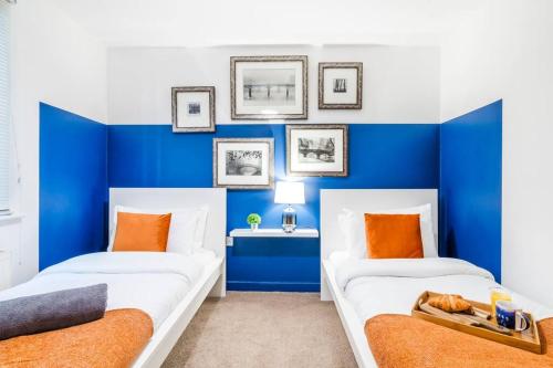 two beds in a room with blue walls at Sapphire Retreat - Central Location - Free Parking, FastWiFi and Smart TV by Yoko Property in Derby