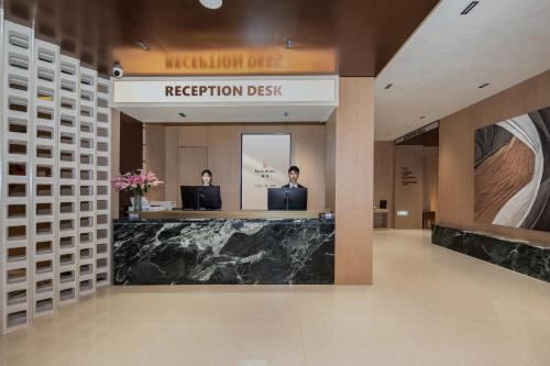 two people sitting at a reception desk in a building at Relax Hotel - Shenzhen Bao'an International Airport in Bao'an