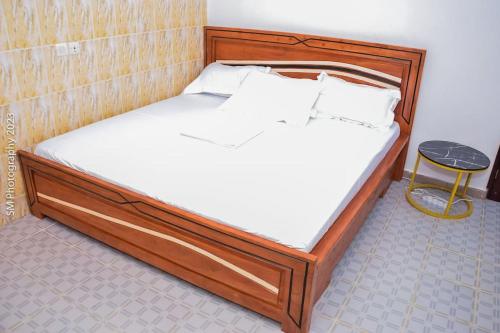 a bed with a wooden frame and white sheets at Sweet and cozy in Cotonou