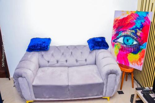 a couch in a room with a painting of an eye at Sweet and cozy in Cotonou