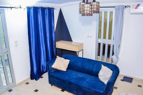 a blue couch in a living room with blue curtains at Sweet and cozy in Cotonou