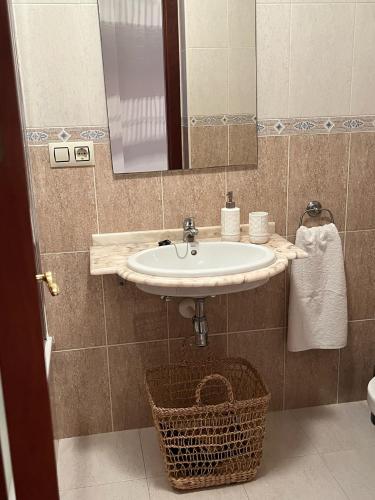 a bathroom with a sink and a mirror and a basket at Casa das Sereas in Laxe