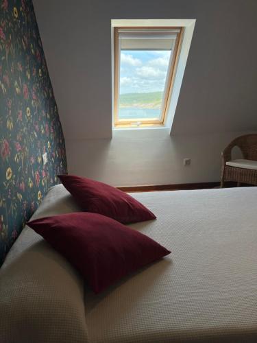 a bedroom with a bed with red pillows and a window at Casa das Sereas in Laxe
