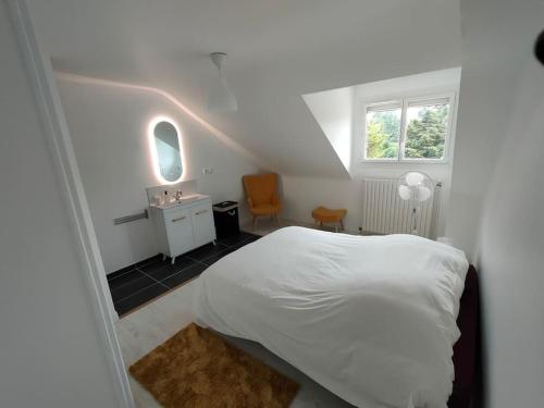 - une chambre blanche avec un lit blanc et un lavabo dans l'établissement *Gîte Aux Grappes du Pressoir* à 2 km de Beauval, à Seigy