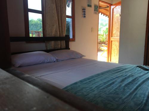 a large bed in a room with a window at Hostal Los Wichos in Minca
