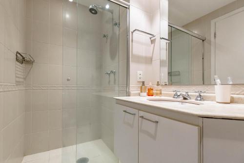 baño blanco con ducha y lavamanos en Itaim Bibi Club Hoteling, en São Paulo