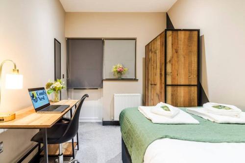 Cette chambre comprend deux lits et un bureau avec un ordinateur portable. dans l'établissement Wiverton Apt #2 - Central Location - Free Parking, Fast WiFi and Smart TV by Yoko Property, à Nottingham