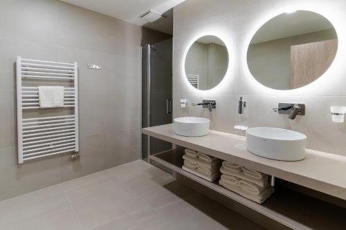 a bathroom with two sinks and two mirrors at Spa & Wellness Hotel Fitak**** in Liptovský Ján