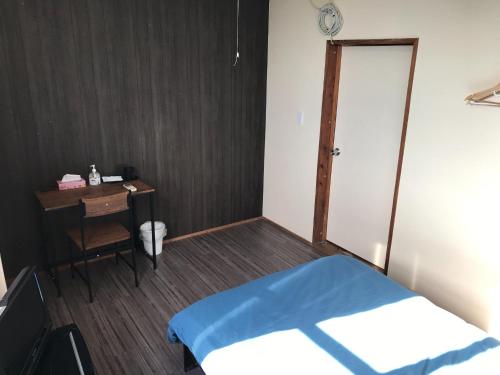 sypialnia z łóżkiem, biurkiem i drzwiami w obiekcie Minshuku Green-so - Vacation STAY 92548v w mieście Uechi