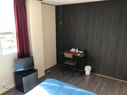Pokój z łóżkiem i biurkiem z telewizorem w obiekcie Minshuku Green-so - Vacation STAY 92548v w mieście Uechi