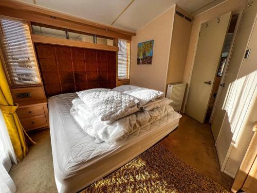 um quarto com uma cama grande e lençóis brancos em Great Caravan For Hire With Pond Views At Manor Park Holiday Park Ref 23228k em Hunstanton
