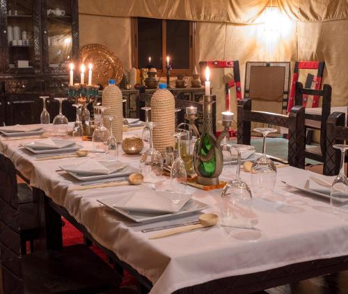 a table with a white table cloth and candles on it at Merzouga luxury magic nights in Merzouga