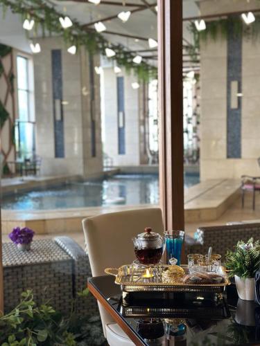 a table with a tray of food and a swimming pool at Violet Al Azizia Hotel MASJID Al Qatari in Makkah