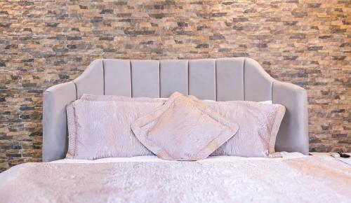 a white bed with pink pillows and a brick wall at Agva Teras Garden Hotel & Bungalow in Agva